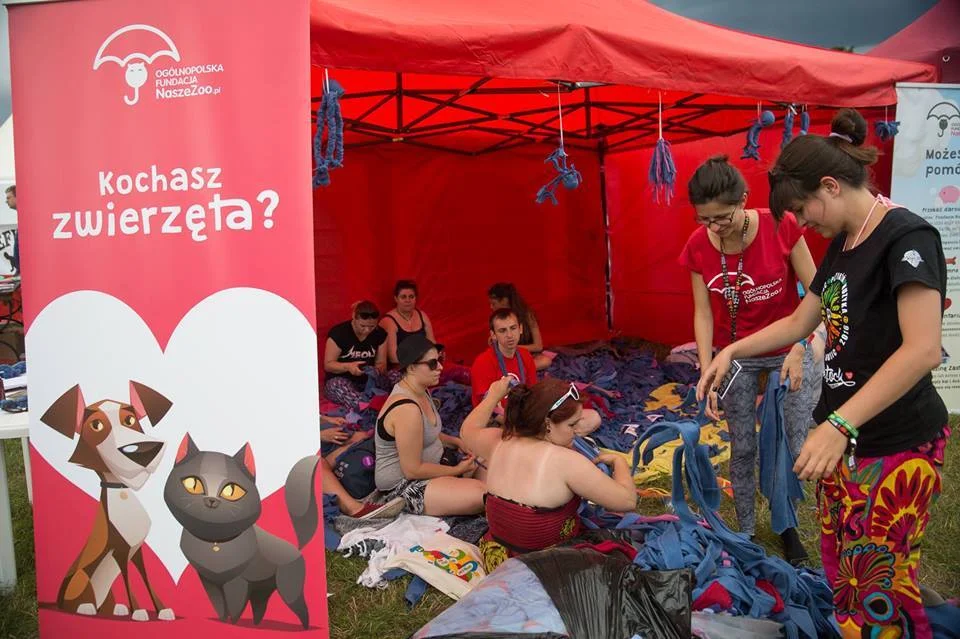 Namiot fundacji na festiwalu z banerem Kochasz zwierzęta i uczestnikami przy pracy